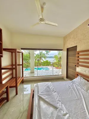 a bedroom with a bed and a view of the ocean at GroveStay in Chakkarakkal