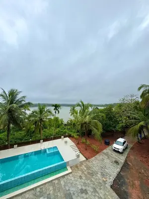 a villa with a swimming pool and a car at GroveStay in Chakkarakkal