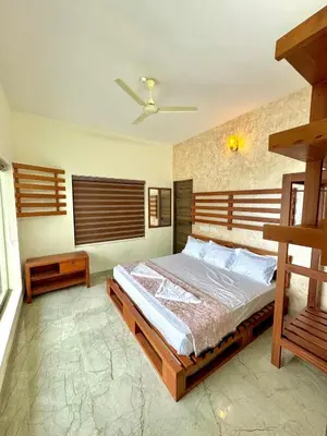 a bedroom with a bed and a ceiling fan at GroveStay in Chakkarakkal