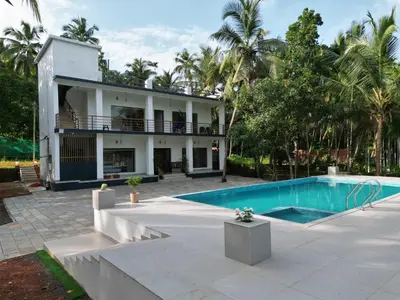 a house with a swimming pool in front of it at GroveStay in Chakkarakkal