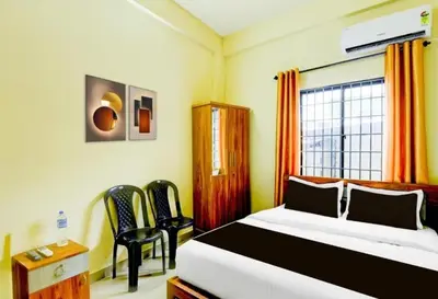 a bedroom with a bed and two chairs and a window at RK Residency in Kozhikode