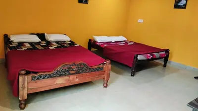 two beds with red sheets in a room at Aryas comforts near Gumbaz in Shrīrangapattana