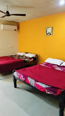 two beds in a room with yellow walls at Aryas comforts near Gumbaz in Shrīrangapattana