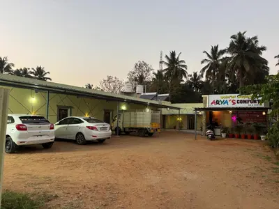 a building with two cars parked in front of it at Aryas comforts near Gumbaz in Shrīrangapattana