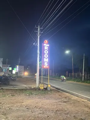 a neon motel sign on the side of a road at Aryas comforts near Gumbaz in Shrīrangapattana