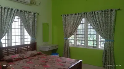 a bedroom with green walls and a bed and two windows at Mannath Home stay in Alwaye