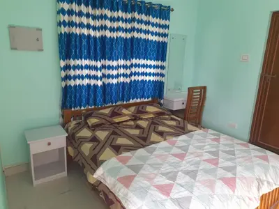 a bedroom with a bed and a blue curtain at Mannath Home Stay in Alwaye