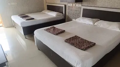 two beds in a hotel room with white sheets at Hotel BMR Stay in Pollāchi