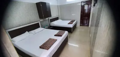 a room with two beds in a room with a mirror at Hotel BMR Stay in Pollāchi