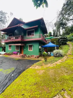 a green house with a black roof at Quiet quarters Estate Stay in Napoklu
