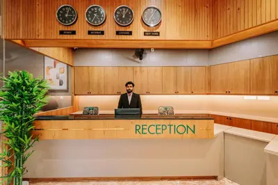 a man in a suit sitting at a reception desk at Hotel Urban Bella in Kozhikode