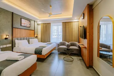 a hotel room with two beds and a tv at Hotel Urban Bella in Kozhikode