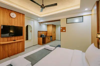 a bedroom with a white bed and a tv at Hotel Urban Bella in Kozhikode