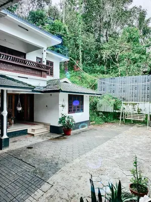 a white house with a patio in front of it at Banasura Green paradise , Villa , Deluxe rooms , Budget rooms in Padinjarathara