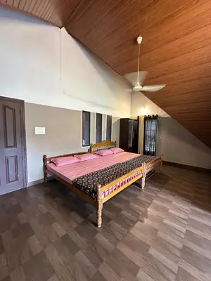a large bed in a room with a wooden ceiling at Cottage on Riverside in Irinjālakuda