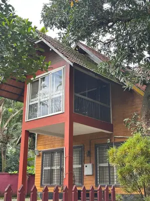 a house with a red fence in front of it at Cottage on Riverside in Irinjālakuda