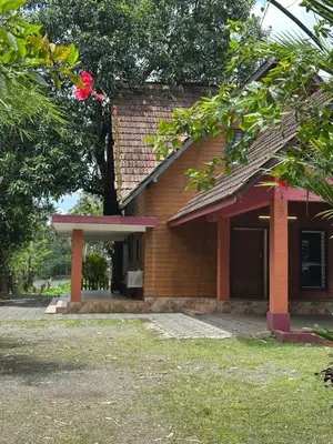 a brick house with a red roof and a tree at Cottage on Riverside in Irinjālakuda
