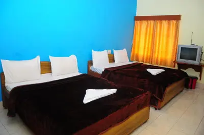 two beds in a hotel room with a tv at Hotel Zaraa in Ooty