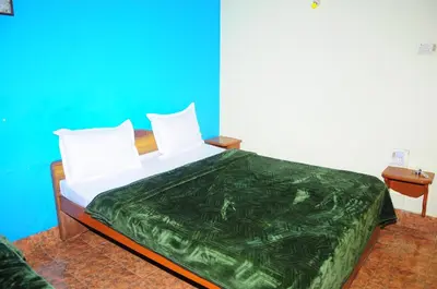 a bedroom with a bed with a green comforter at Hotel Zaraa in Ooty