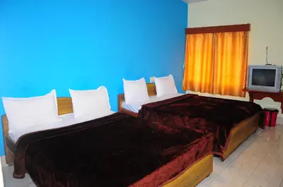 two beds in a room with a tv at Hotel Zaraa in Ooty