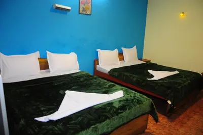 two beds in a room with white pillows at Hotel Zaraa in Ooty