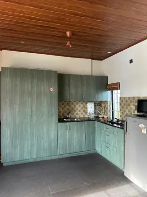 a kitchen with green cabinets and a wooden ceiling at Pearl Spot in Alwaye
