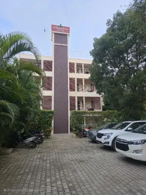 a building with cars parked in front of it at Suraksha Suites in Mysore