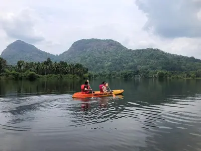 two people in a kayak on a body of water at Nature's nest in Kuttampuzha