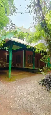 a building with green columns and a green roof at Tejana villa in Mananthavady