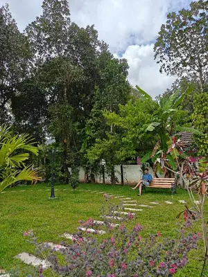 a person sitting on a bench in a park at Full Home Wayanad Bathery in Sultan Bathery