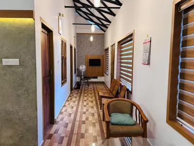 a hallway with chairs and a table and a television at Vayalil Homestay in Karuvārakundu