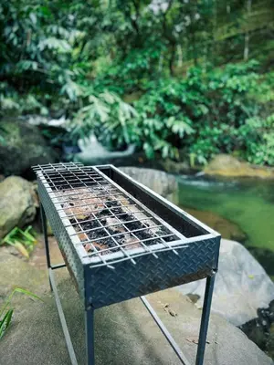 a metal grill sitting on a rock next to a river at Vayalil Homestay in Karuvārakundu