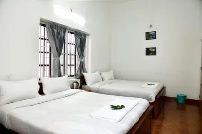 a room with two beds and a window at Mountain Villa Ooty Rooms in Ooty