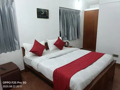 a bedroom with a large bed with red pillows at Mountain Villa Ooty Rooms in Ooty