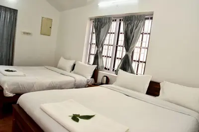 a hotel room with two beds and a window at Mountain Villa Ooty Rooms in Ooty