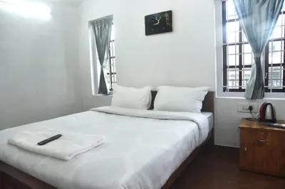 a bedroom with a white bed with a phone on it at Mountain Villa Ooty Rooms in Ooty