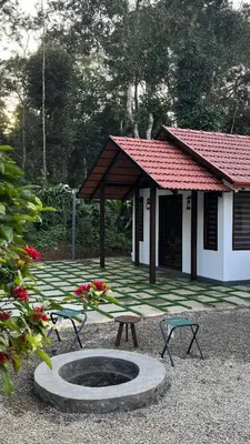 a patio with two chairs and a table and a building at Coorg Robusta Retreat in Suntikoppa