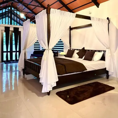 a bedroom with a canopy bed with curtains and a rug at Coorg Robusta Retreat in Suntikoppa