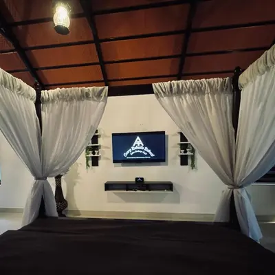 a bedroom with a bed with curtains and a tv at Coorg Robusta Retreat in Suntikoppa