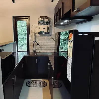 a kitchen with black cabinets and a sink at Coorg Robusta Retreat in Suntikoppa