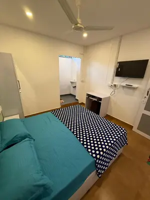 a bedroom with a bed and a desk and a television at AAN GREENS Rooms And Dormitorys in Vaduvanchal