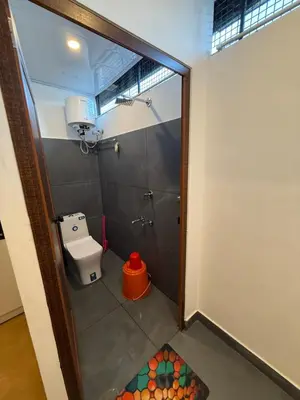 a small bathroom with a toilet and a shower at AAN GREENS Rooms And Dormitorys in Vaduvanchal