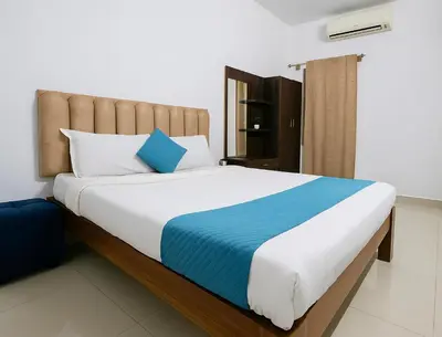 a bedroom with a large bed with blue and white pillows at Cozy retreat in Mysore
