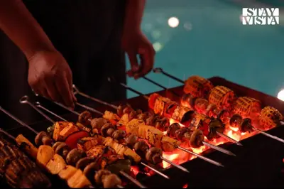 a person is cooking food on a grill at StayVista at Rustling Pine with Bonfire, BBQ & Lawn in Ooty