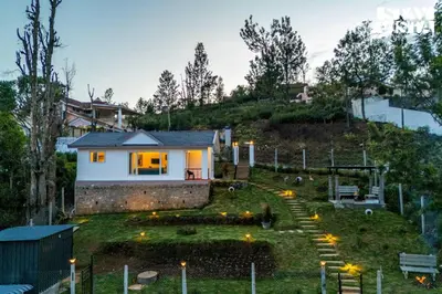 a house on a hill with lights in the yard at StayVista at Rustling Pine with Bonfire, BBQ & Lawn in Ooty