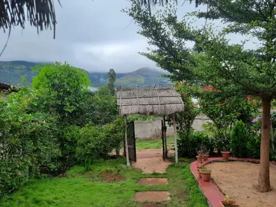 a garden with a hut with a view of the mountains at Mannora Resorts Marayoor in Marayoor