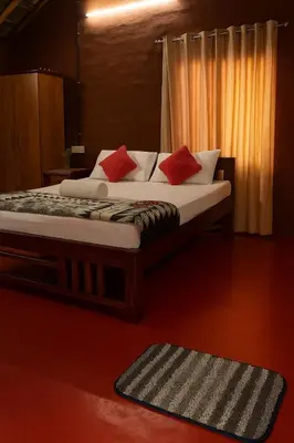 a bedroom with a bed with red pillows on it at Mannora Resorts Marayoor in Marayoor