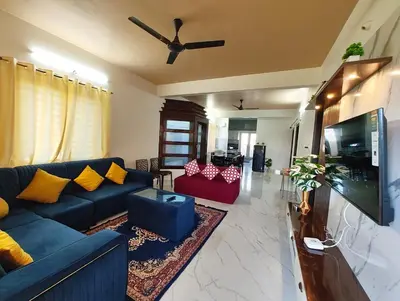 a living room with a blue couch and a flat screen tv at Luxurious 3BHK AC, Peaceful location, Premium stay in Mysore