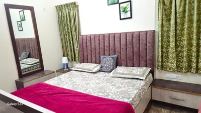 a bedroom with a bed with two pillows and a mirror at JEO Home Stay And Hospitality in Mysore