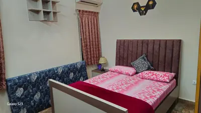 a small bedroom with a bed with pink sheets at JEO Home Stay And Hospitality in Mysore